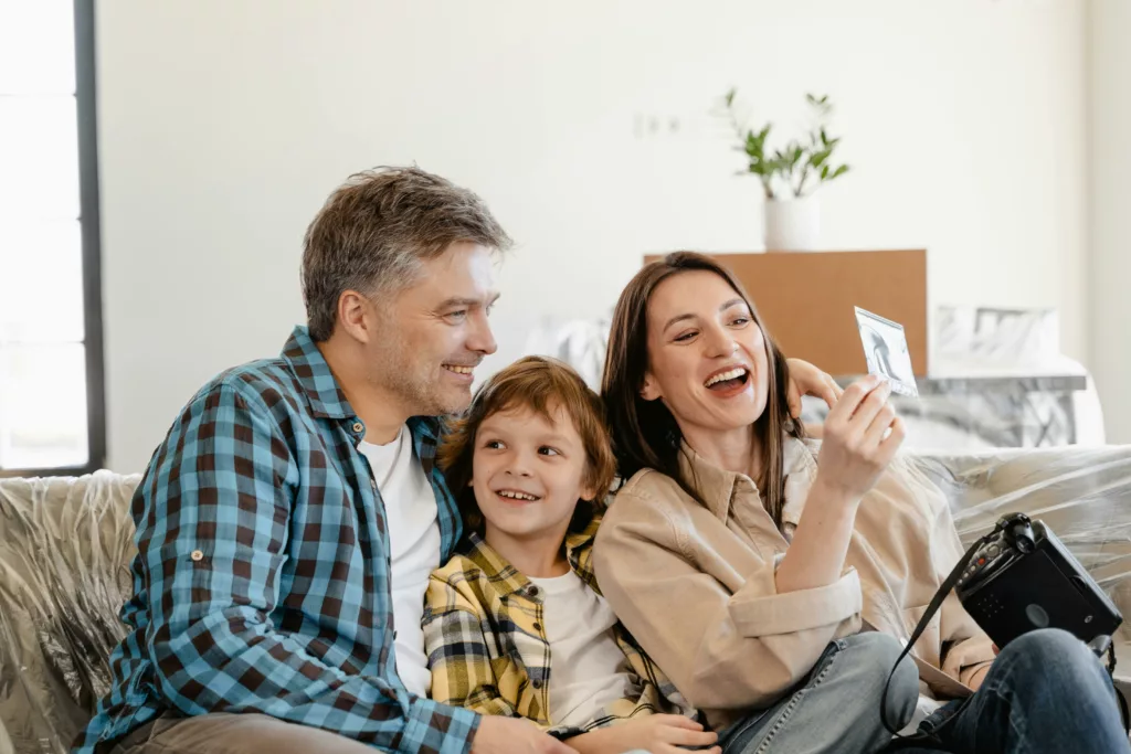 pexels-photo-7415122-7415122-1 A cheerful family enjoys time together on a couch surrounded by moving boxes in their new home.
